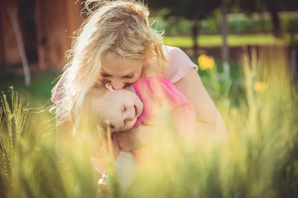 Mãe segurando e beijando bebê menina — Fotografia de Stock