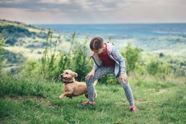 Bir çayır üzerinde bir köpekle oynayan kız