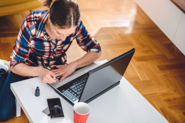 Kahve masasında katta oturan ve çivi boya kareli gömlek giyen kadın