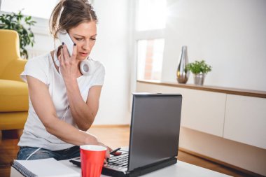 Kahve masada oturan ve evde akıllı telefonda konuşurken beyaz gömlek giyen kadın