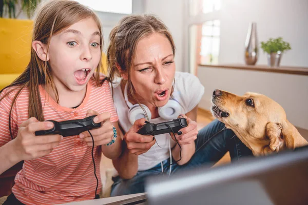 Mother and daughter playing video games on laptop at home