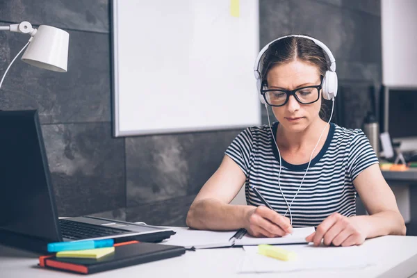 Mulher Usando Óculos Escrevendo Notas Ouvindo Música Escritório — Fotografia de Stock