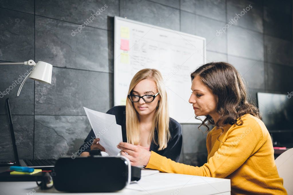 Two business women working at office and checking paperwork at the desk