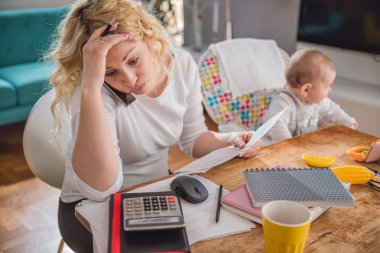 Mektup holding, not yazma, office evde akıllı telefonda konuşurken ve onun Bebek Bakımı endişeli anne
