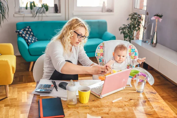 Madre Vistiendo Anteojos Sentada Escritorio Con Bebé Usando Teléfono Inteligente — Foto de Stock