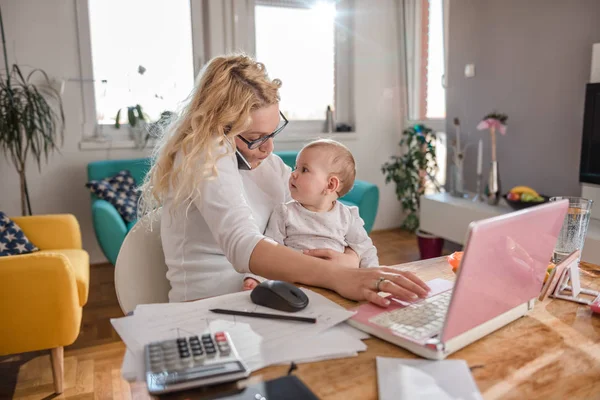 Mama Ține Copilul Vorbește Telefonul Inteligent Birou Acasă Folosind Laptopul — Fotografie, imagine de stoc