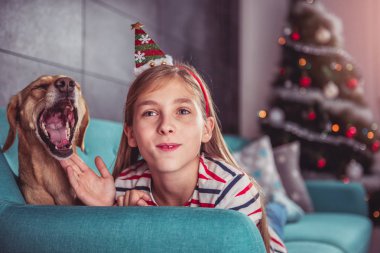 Küçük kız Santa şapka ile bir küçük sarı esneme köpek