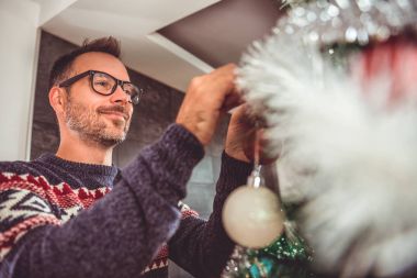 yakışıklı adam Mavi kazak ve Noel ağacı evde dekorasyon gözlük takıyor