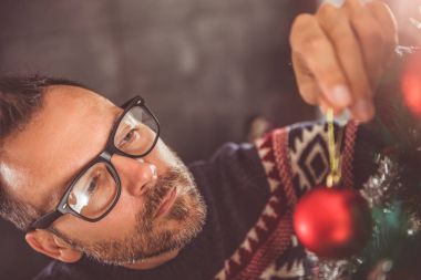 yakışıklı adam Mavi kazak ve Noel ağacı evde dekorasyon gözlük takıyor