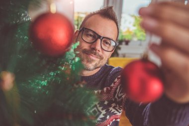 yakışıklı adam Mavi kazak ve Noel ağacı evde dekorasyon gözlük takıyor