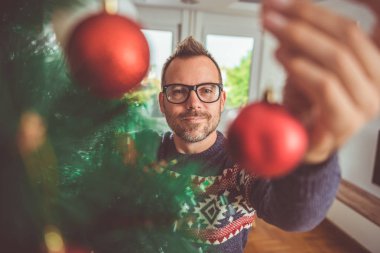 yakışıklı adam Mavi kazak ve Noel ağacı evde dekorasyon gözlük takıyor