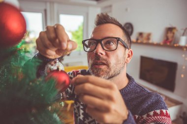 yakışıklı adam Mavi kazak ve Noel ağacı evde dekorasyon gözlük takıyor