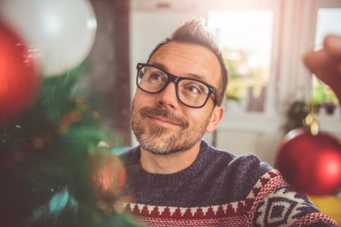 yakışıklı adam Mavi kazak ve Noel ağacı evde dekorasyon gözlük takıyor