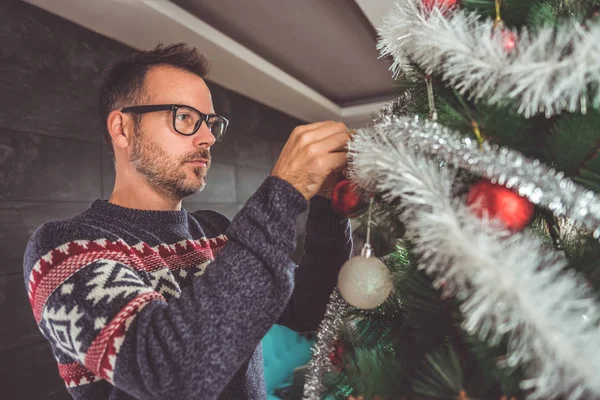 yakışıklı adam Mavi kazak ve Noel ağacı evde dekorasyon gözlük takıyor