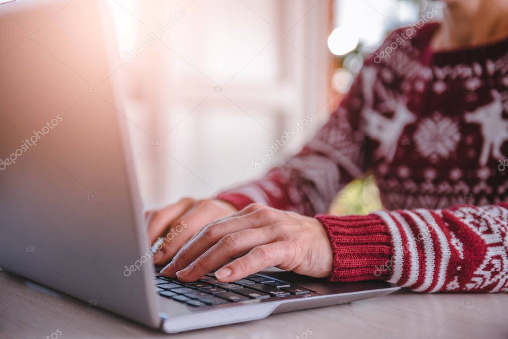 Woman wearing red sweater using laptop at home during christmas
