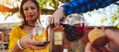 Adam kırmızı şarap sürahi gelen kadın cam arka bahçe veranda, içine dökülen 