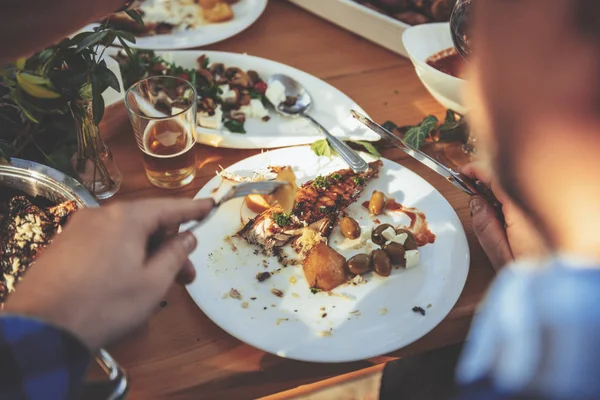 Man eating fish and ships at family lunch outdoor in backyard patio