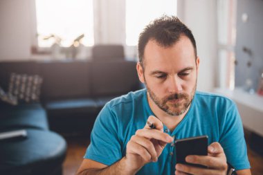 Akıllı telefon kullanarak mavi tişörtlü adam