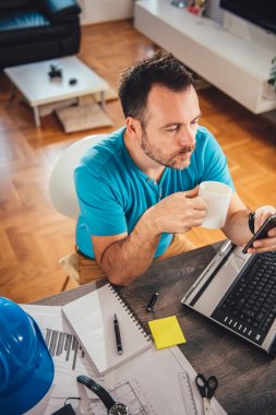 Mavi gömlek akıllı telefon ve holding kahve Kupası evde kullanarak office dostum