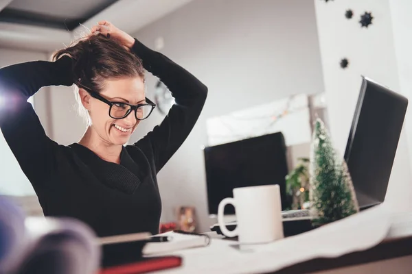 Woman stretching her back at desk in home office