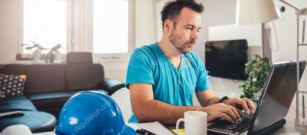 Man in blue shirt using laptop at home office