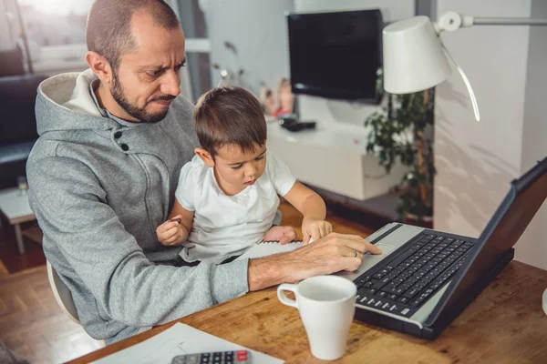 Otec Pracuje Laptop Domácí Kancelář Držení Syna Klíně — Stock fotografie