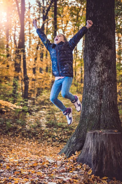 Girl jumping in the forest with hands raised