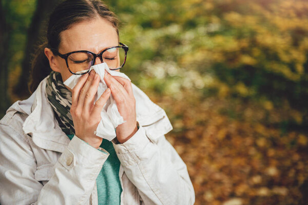 Woman blowing her nose in the park