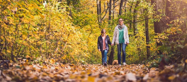 Mother and daughter hiking in a forest with dog