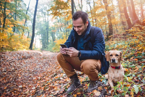 Hombre Cuclillas Junto Pequeño Perro Amarillo Uso Teléfono Bosque Otoño — Foto de Stock