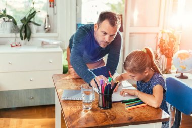 Babası ona ev ödevi bitirmek için yardım kızı yanındaki masaya yalın