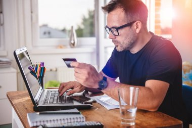 İş adamı, merkez büroda kredi kartı ve laptop kullanıyor.