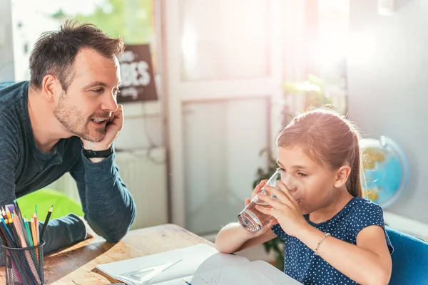 Chica Bebiendo Agua Mientras Hace Tarea Padre Pie Junto Ella — Foto de Stock