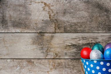 renkli Paskalya yumurta içinde mavi teneke kova ahşap arka plan üzerinde