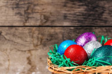 Paskalya yumurta içinde kahverengi ahşap arka plan üzerinde renkli sepet