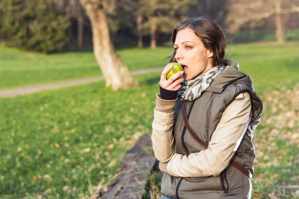 春の公園で青リンゴを持つ若い女性 — ストック写真