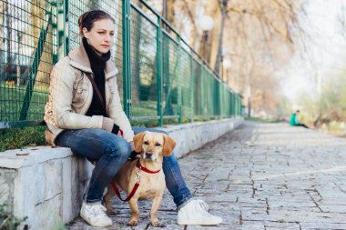 Oturma ve köpeğiyle çitin yanında oturan kadın