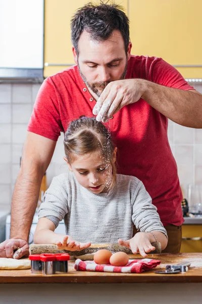 little girl with father making dough at home kitchen
