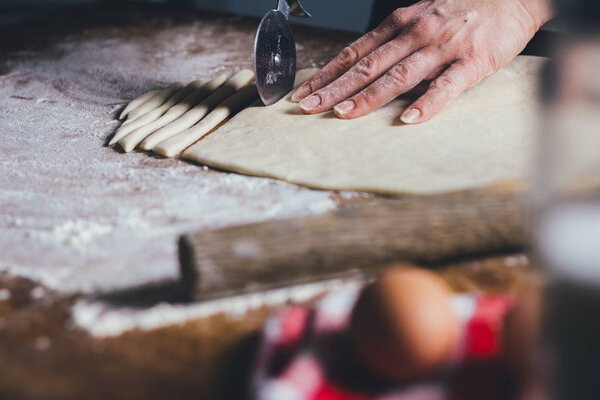 close-up of female hands making cookies from dough at home kitchen