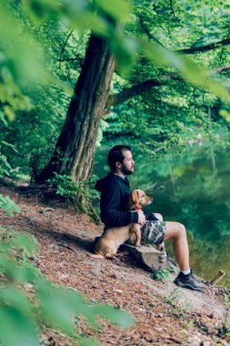 Göl kenarında köpek ile ağaç günlük bankta oturmuş sakallı