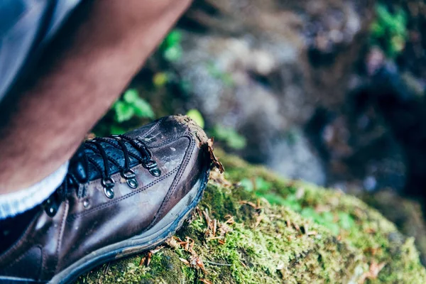 Picture of man muddy and dirty shoe standing on the rock covered with moss