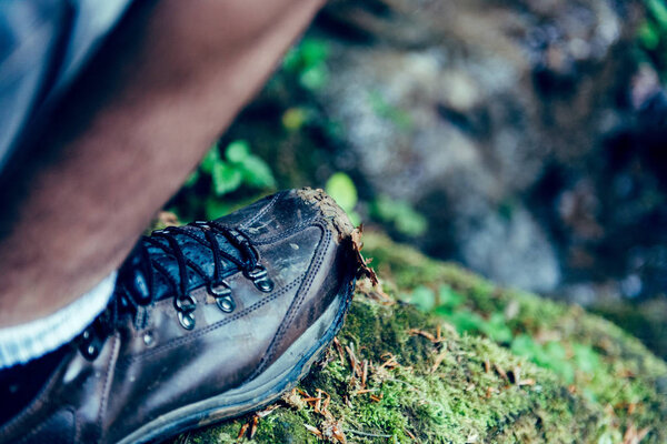 Picture of man muddy and dirty shoe standing on the rock covered with moss 