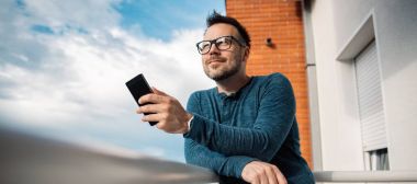 Akıllı telefon açık kullanarak gözlüklü adam. O mavi tişört giyiyor.