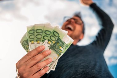 Mavi gömlek giymiş gözlüklü adam. ve para yığını tutan.