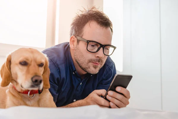 Man Glasses Blue Shirt Laying Bed Dog Using Smart Phone — Stock Photo, Image