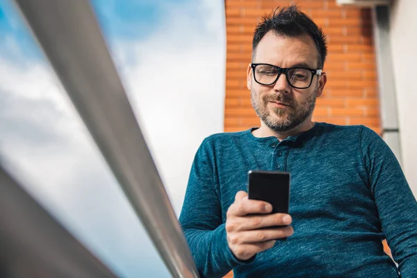 Akıllı Telefon Açık Kullanarak Gözlüklü Adam Mavi Tişört Giyiyor — Stok fotoğraf