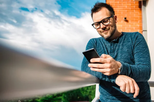 Akıllı Telefon Açık Kullanarak Gözlüklü Adam Mavi Tişört Giyiyor — Stok fotoğraf