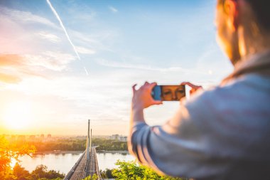 sonbahar günbatımı zaman içinde çok güzel bir köprü arka plan üzerinde telefon kullanan genç kadın