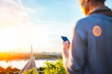 sonbahar günbatımı zaman içinde çok güzel bir köprü arka plan üzerinde telefon kullanan genç kadın