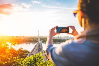 sonbahar günbatımı zaman içinde çok güzel bir köprü arka plan üzerinde telefon kullanan genç kadın   